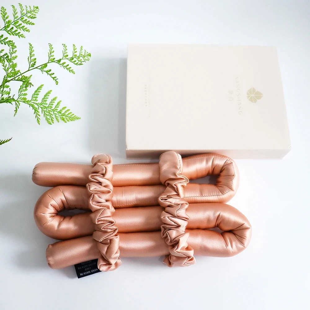 Set of satin-covered hair rollers laid out flat on a white surface