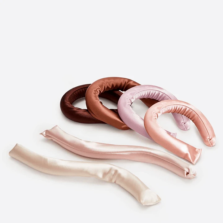 Set of six satin covered heatless hair curler rods laid out flat
