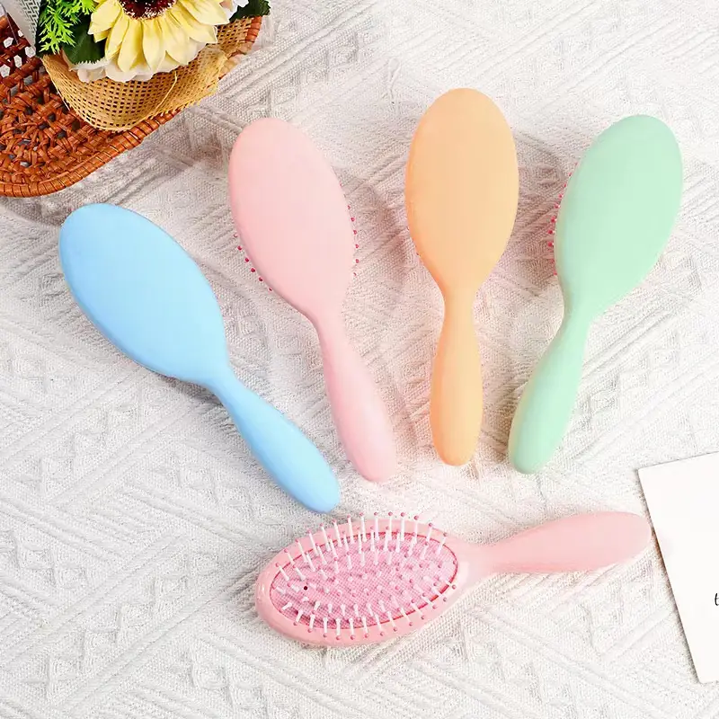 Six macaron-coloured air cushion combs laid out in a row with curved handles