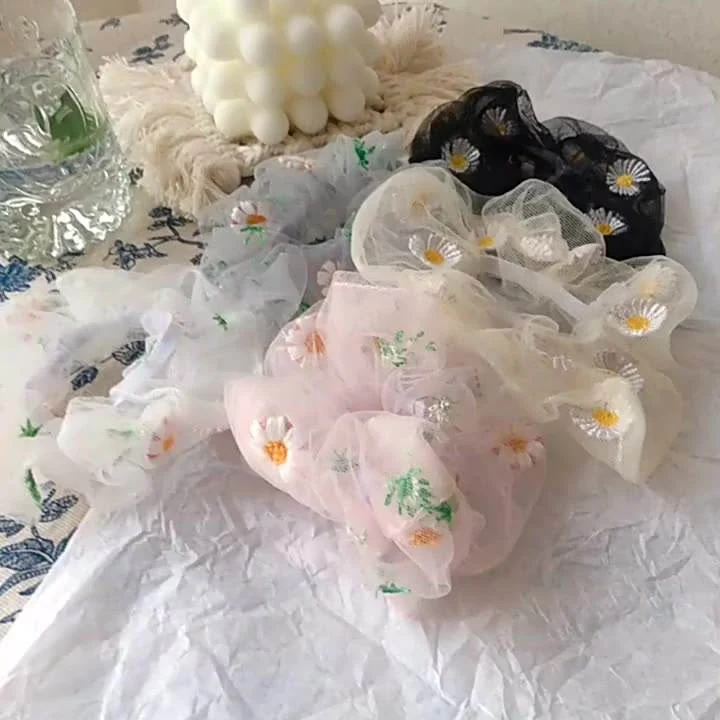 Set of organza hair scrunchies in pink, green and purple laid out flat