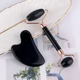 Gua Sha and jade roller tools laid out on a white surface with natural stone texture