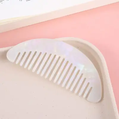 Set of three cellulose acetate combs in different colours laid out on a white surface