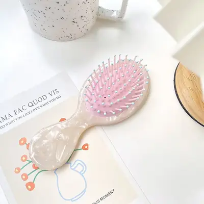 Brush placed next to a hair tie and a satin bonnet to show scale