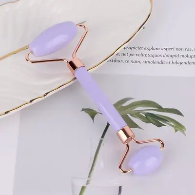 Gua Sha scraper being used on the cheek with a facial serum applied