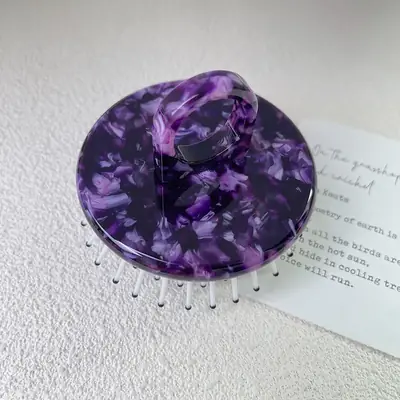 Acetate comb placed on a satin surface with a hair tie and bonnet for styling set