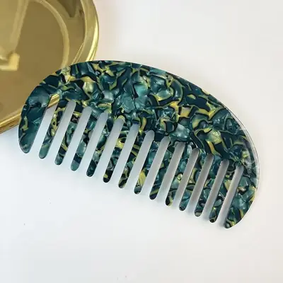 Comb held in hand with fingers showing the rounded tooth design