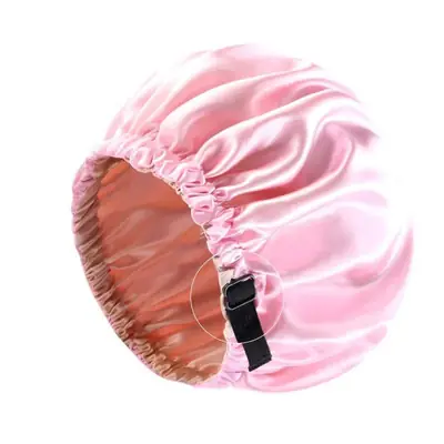 Satin night bonnet worn on a head with the adjustable strap secured