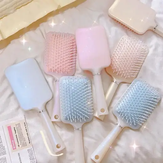 Air cushion comb with soft bristles laid flat on a white surface