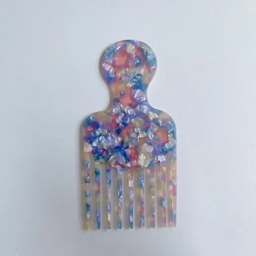 Colorful cellulose acetate wide-tooth hair pick comb laid flat on a white surface