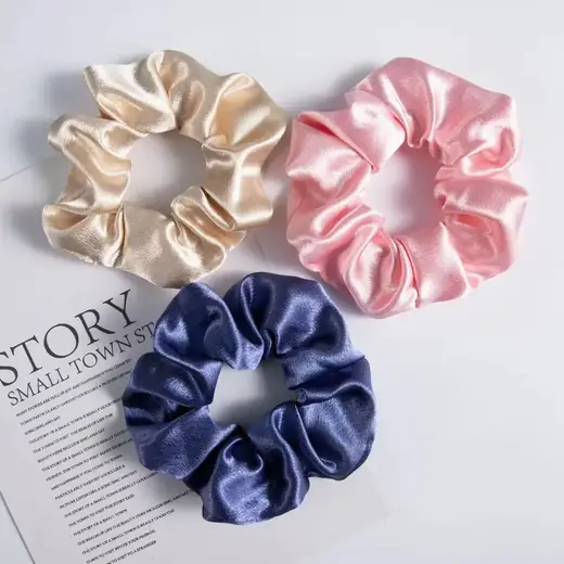 Four 4cm wide mulberry silk scrunchies laid out flat in solid colours