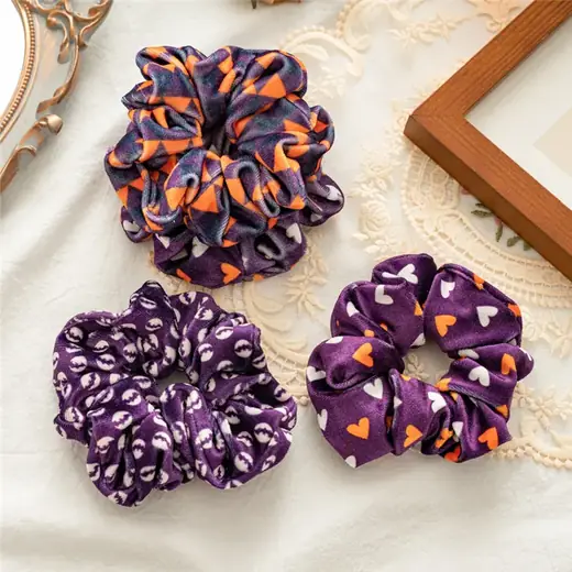 Close-up of a flannel hair scrunchie with pumpkin and bat print on a white background