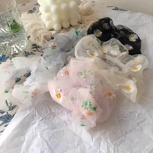 Set of organza hair scrunchies in pink, green and purple laid out flat