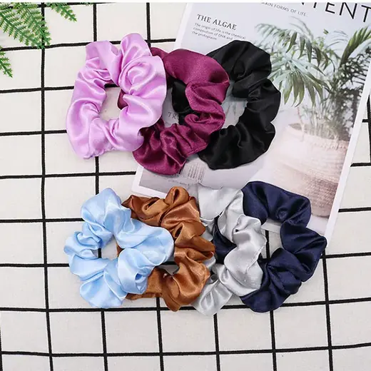 Set of satin surface hair scrunchies with meatball-shaped heads laid out flat