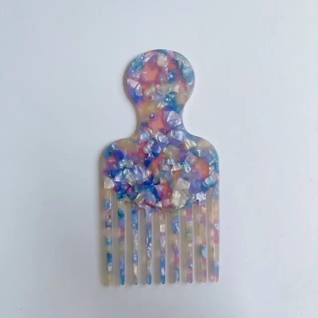 Colorful cellulose acetate wide-tooth hair pick comb laid flat on a white surface