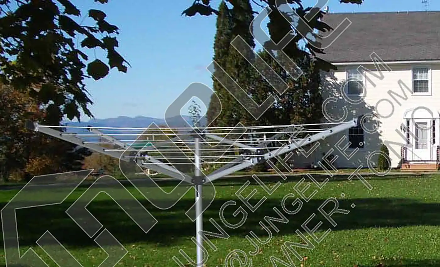 Aluminium camping dryer standing on a lawn beside a white picket fence