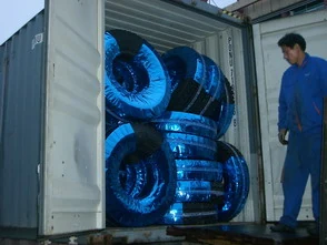 Workers loading wrapped tyres into an export container