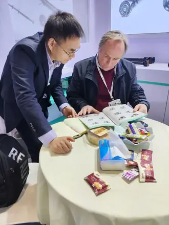 Buyer and supplier reviewing parts across a meeting table at a trade fair