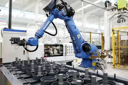 Industrial robot loading machined shaft components onto a fixture