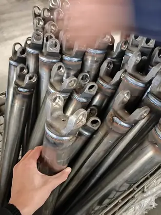 Hand checking the yoke end of a shaft tube against a stack of machined blanks