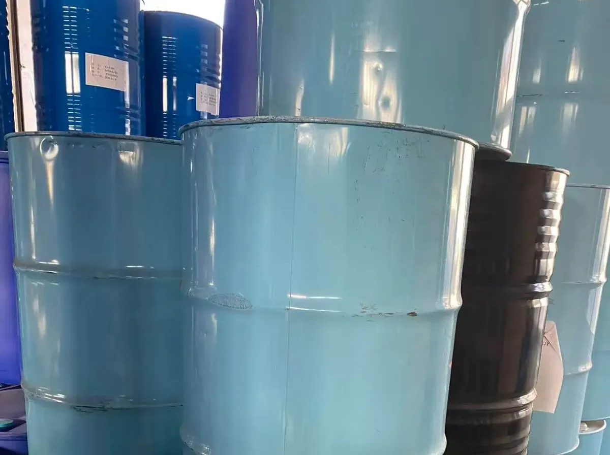 Teal and black steel drums of polyol raw material stacked in a store