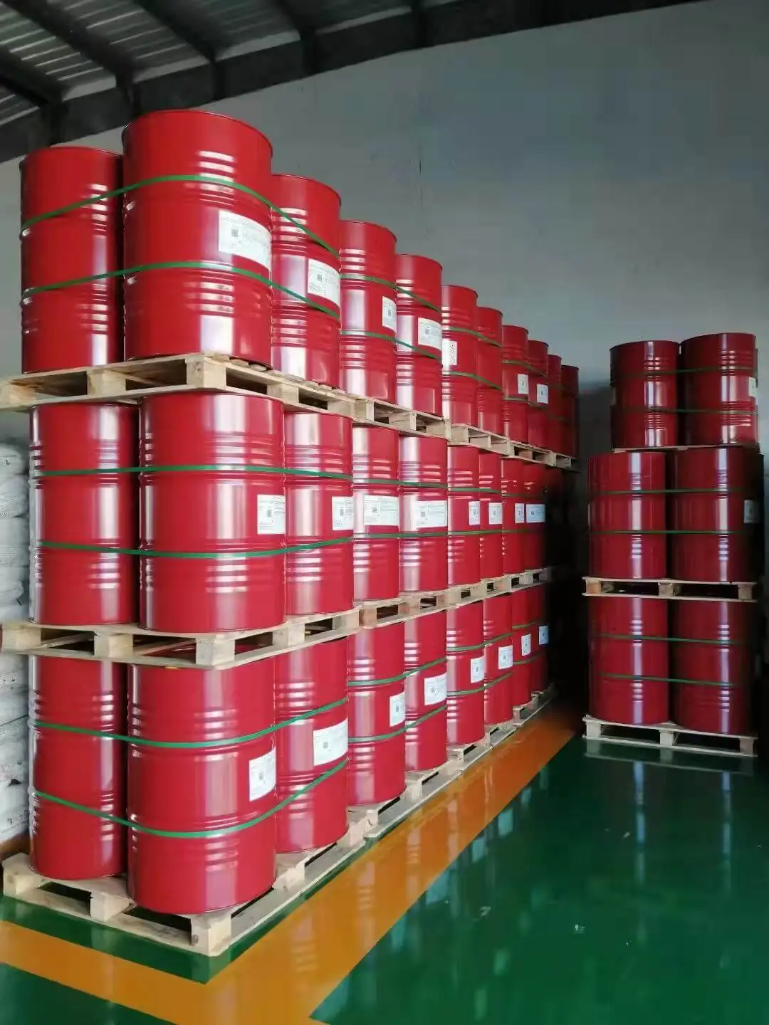 Red drums of IPDI trimer curing agent stacked on pallets in a plant store