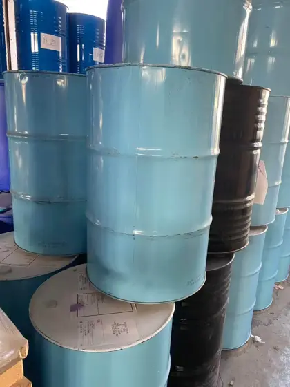 Teal and black steel drums of polycaprolactone polyol stacked in a store
