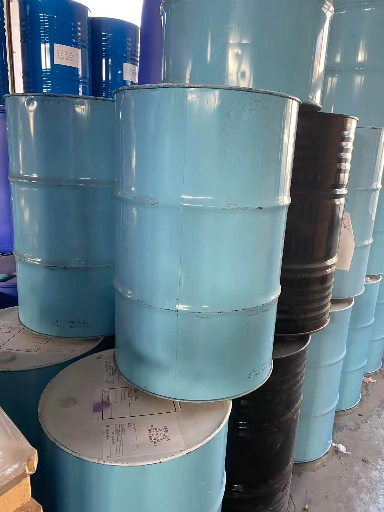 Teal and black polyol drums stacked in a chemical storage area