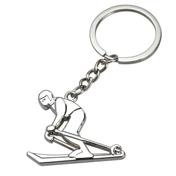 Silver metal skier charm keychain on a split ring, white background