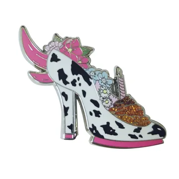 Glitter enamel pin shaped like a cow print heeled shoe with wings