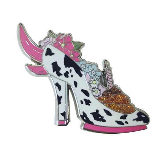 Glitter enamel pin shaped like a cow print heeled shoe with wings