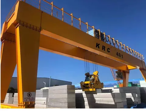 Gantry crane straddling a load in an outdoor yard