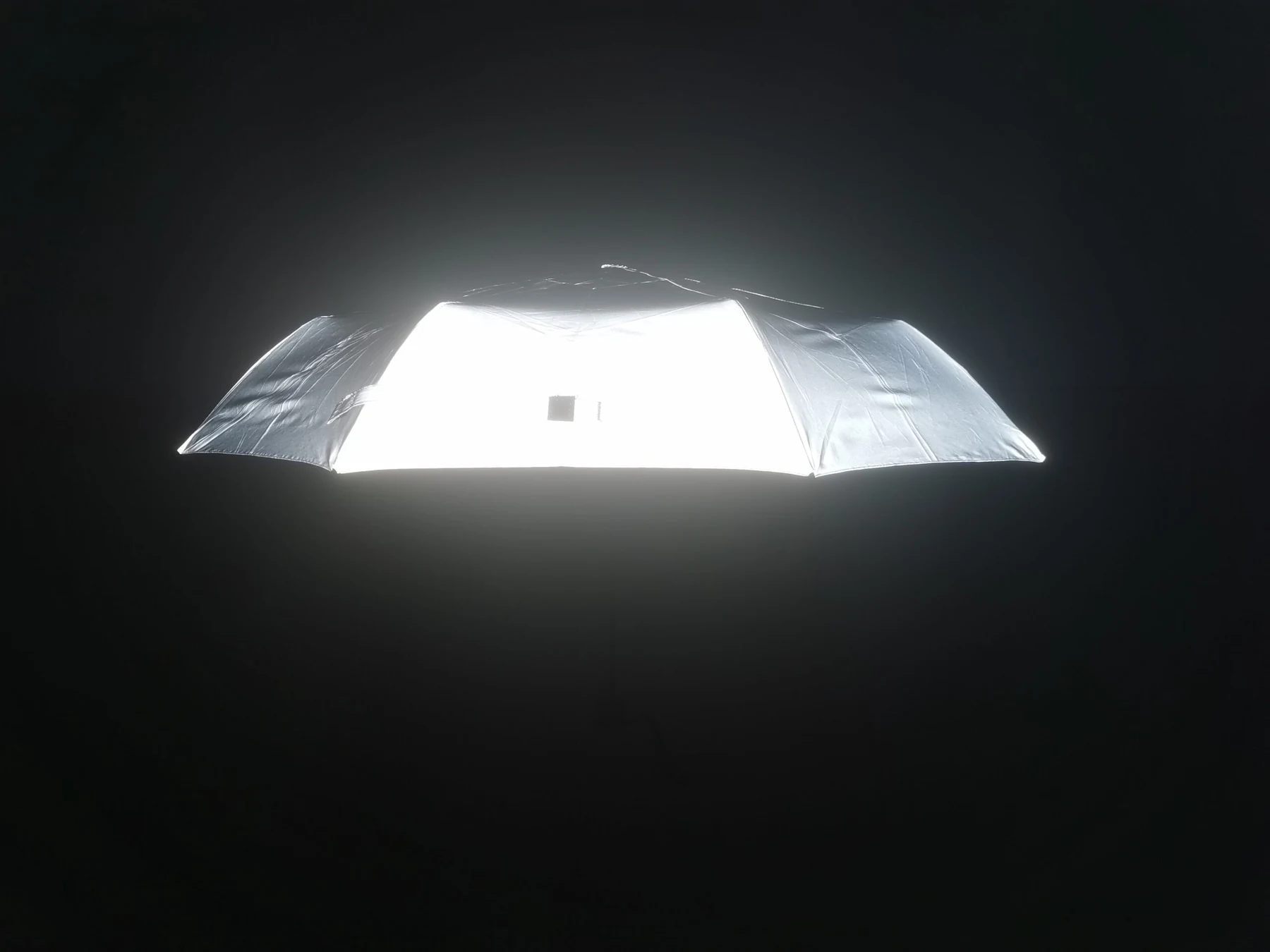 Reflective umbrella canopy glowing brightly against a dark background