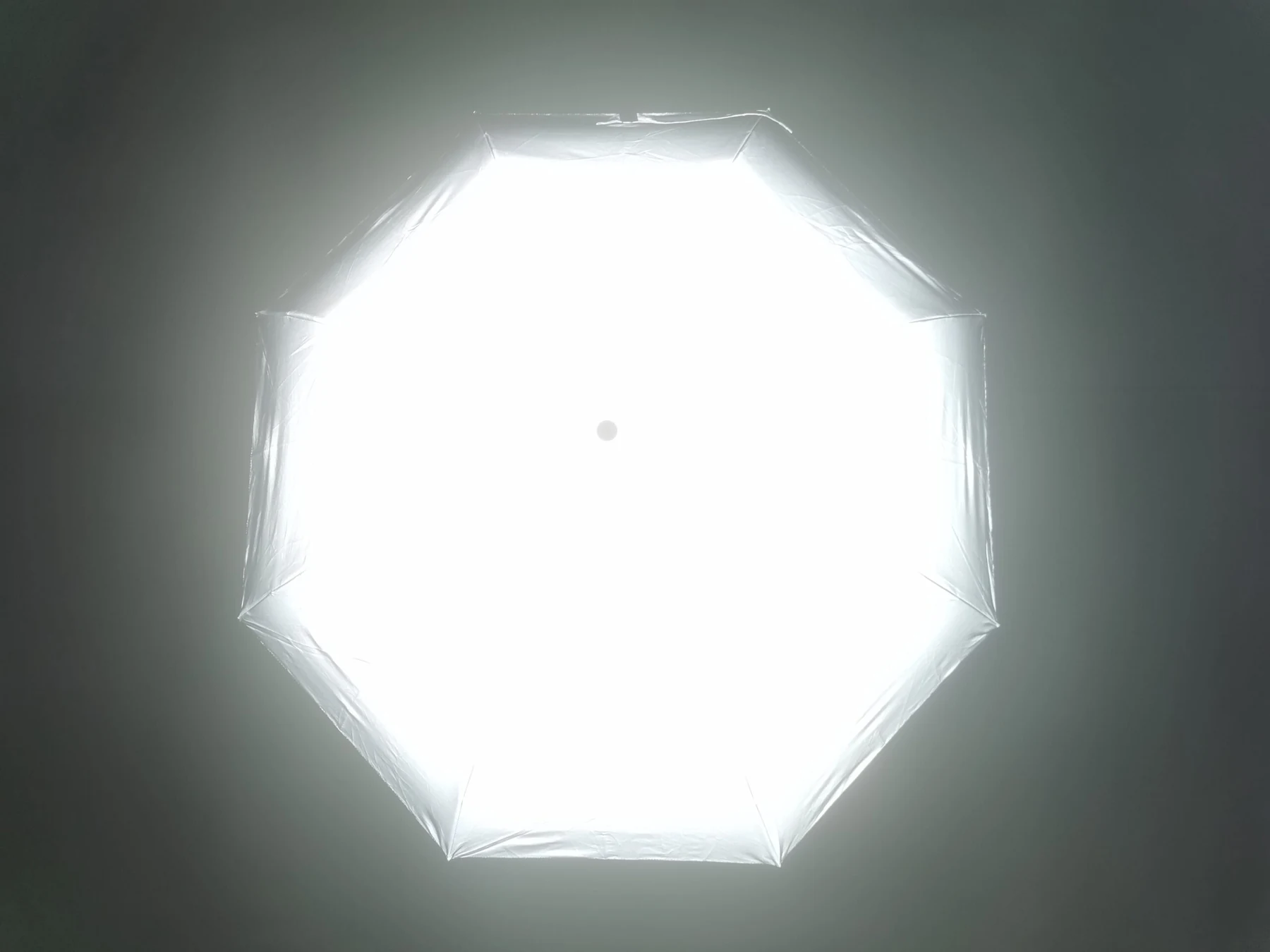 Eight-panel reflective umbrella canopy photographed from above in the dark