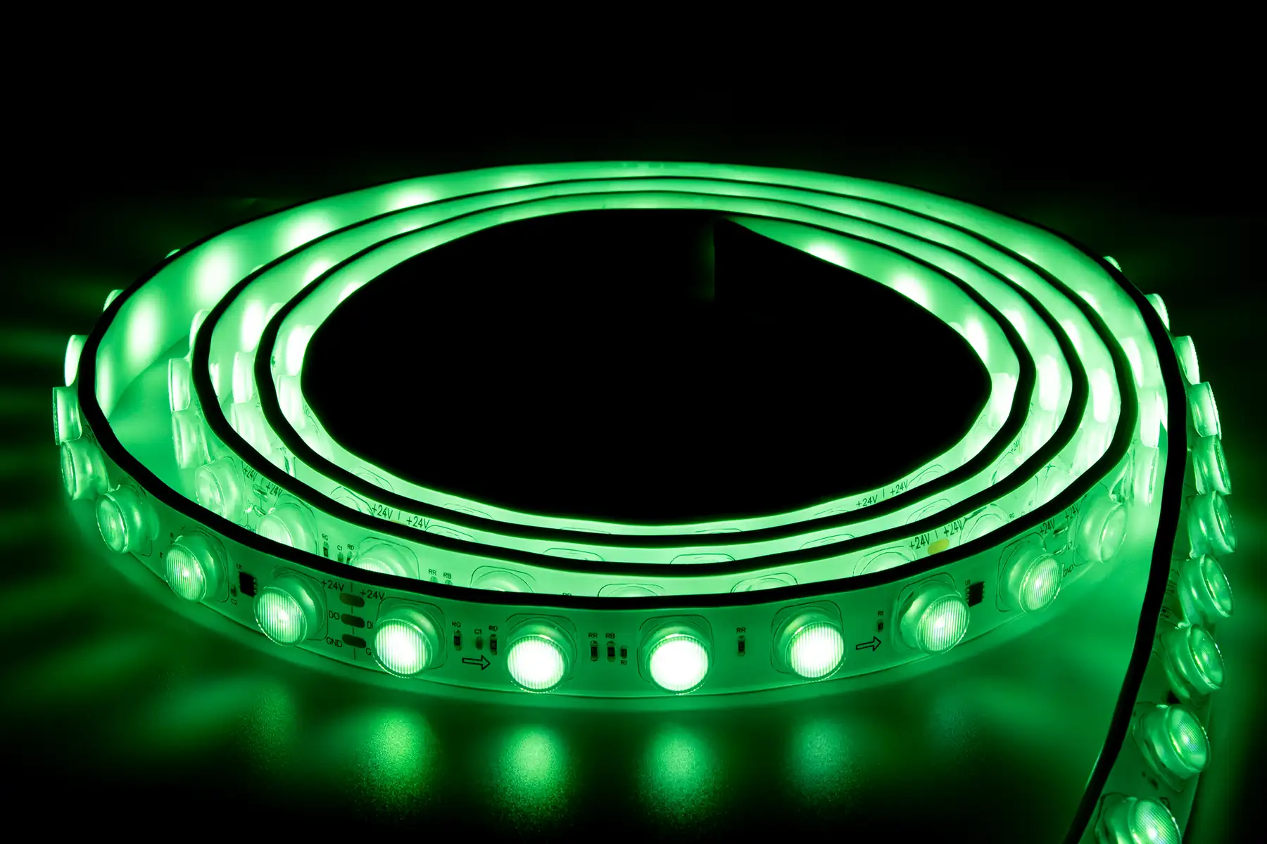 Coiled RGB LED strip lit in green against a dark background