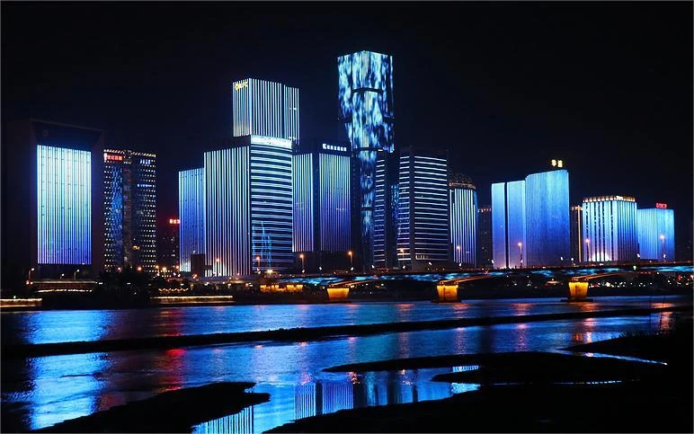 City waterfront at night with illuminated tower facades reflected in water