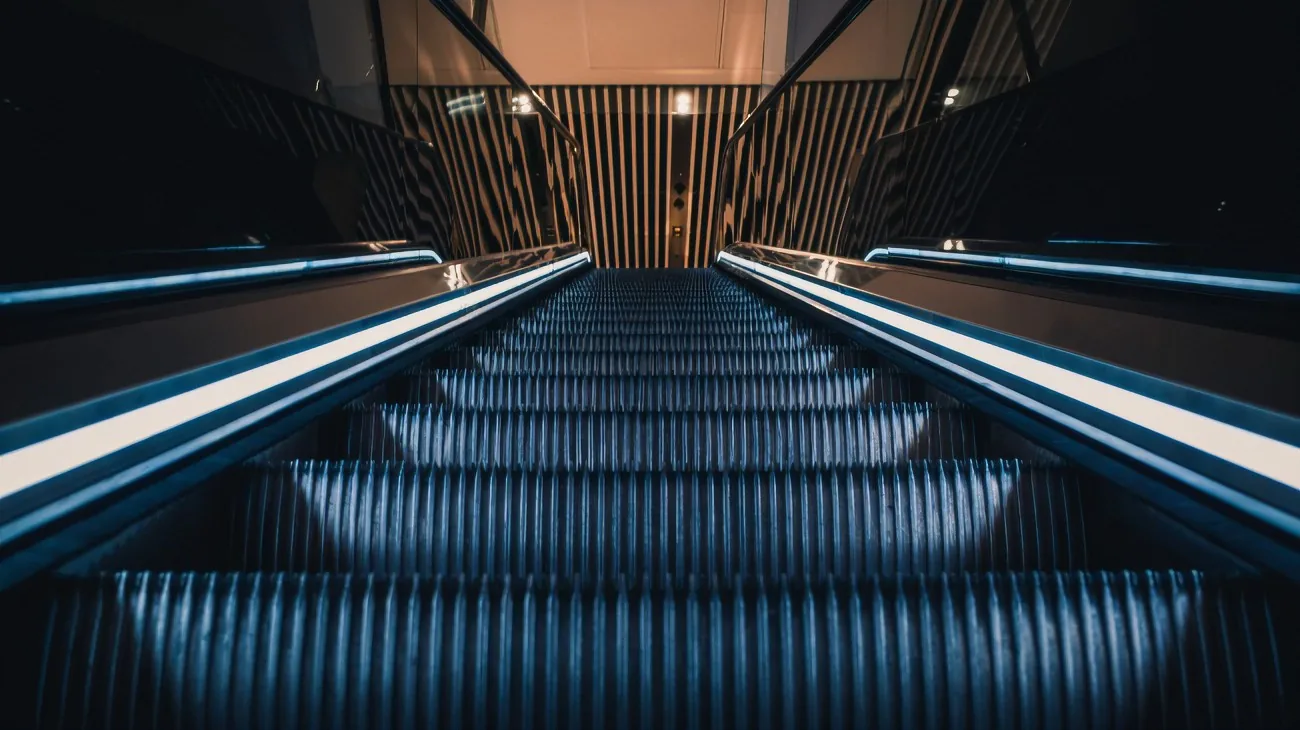 Escalator hall lit with linear LED strip lighting along the balustrade