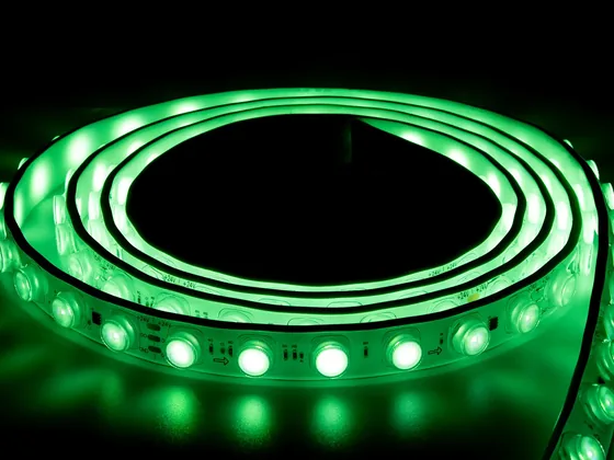 Coiled RGB LED strip lit in green against a dark background