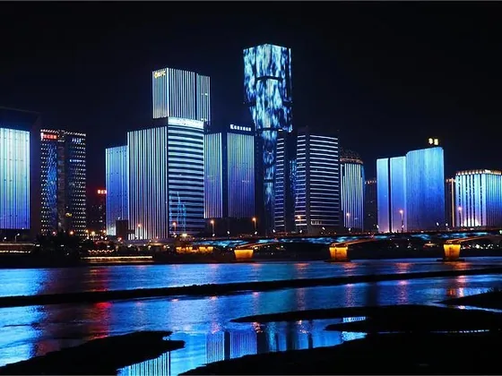 City waterfront at night with illuminated tower facades reflected in water