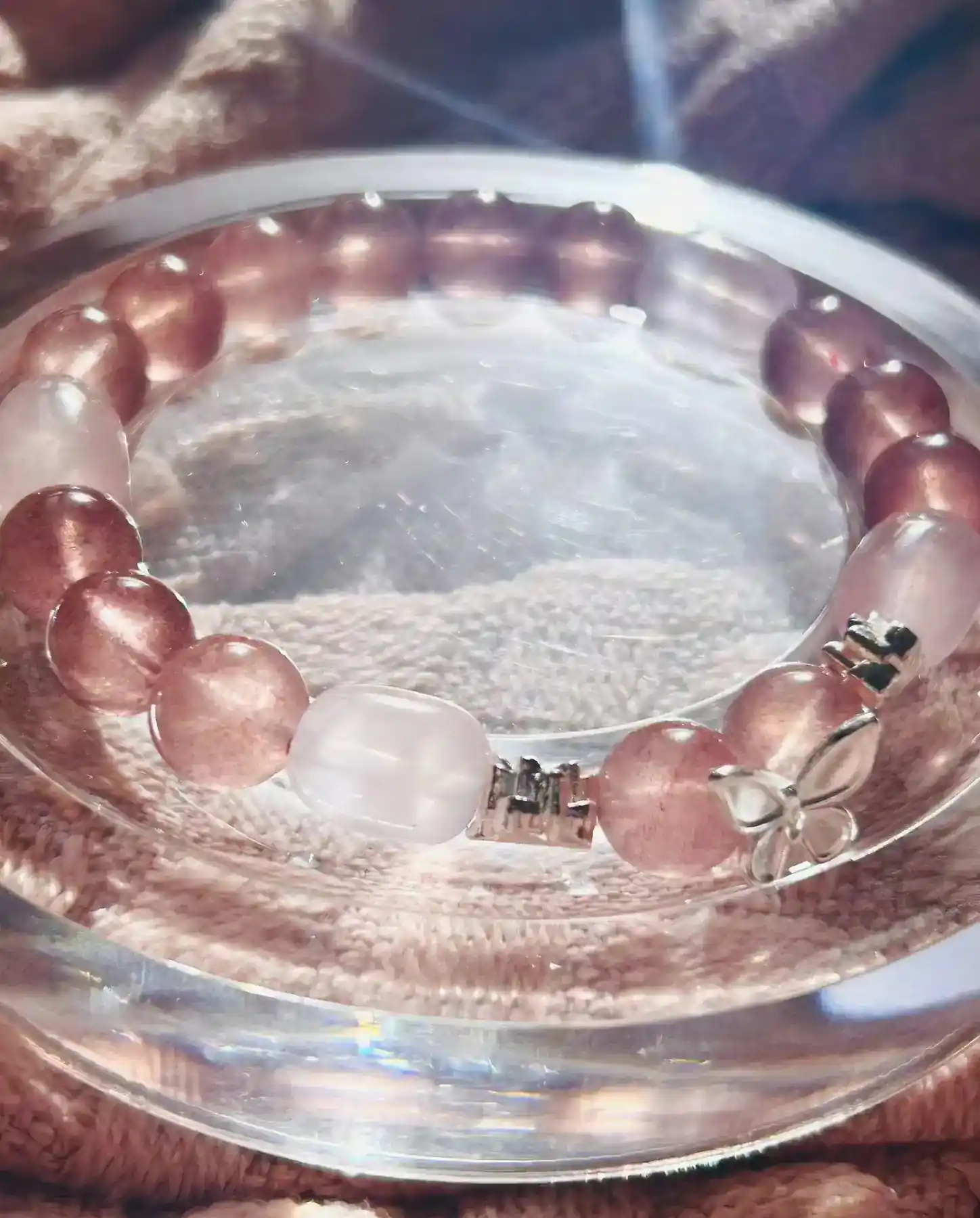 Tender Bond strawberry quartz and rose quartz crystal bracelet, the bracelet styled on a surface