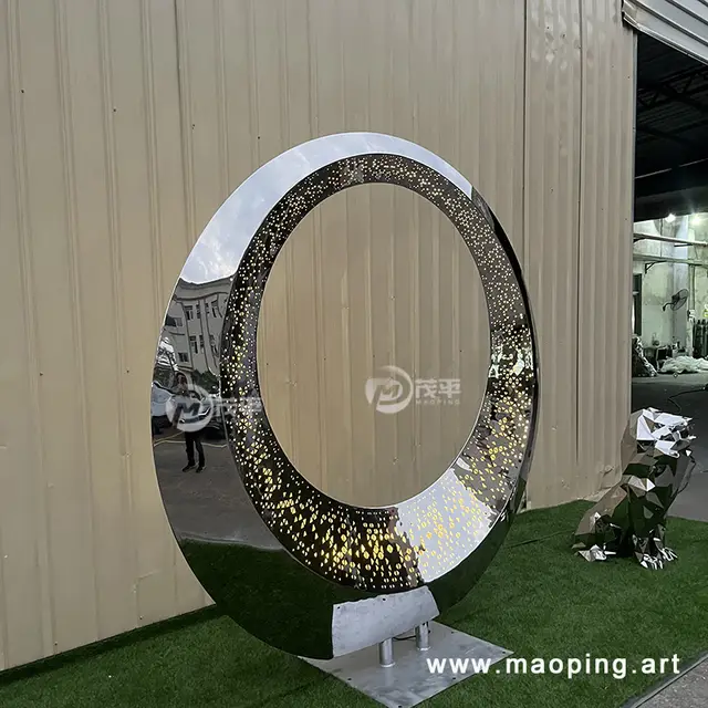 Large outdoor square beach luminous stainless steel ring sculpture seen from another angle