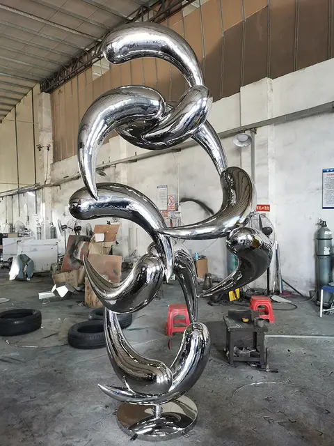 Large outdoor abstract stainless steel fish school sculpture seen from another angle