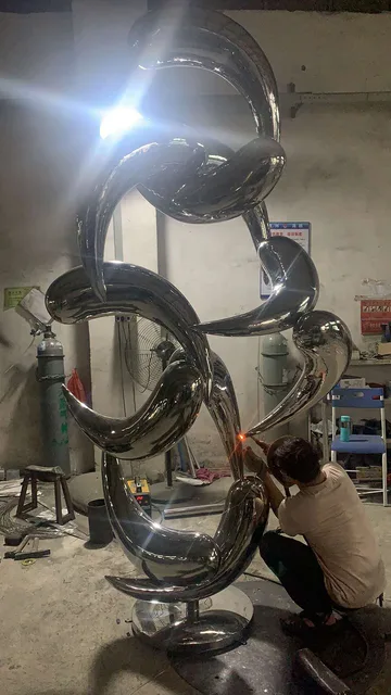Large outdoor abstract stainless steel fish school sculpture in close view