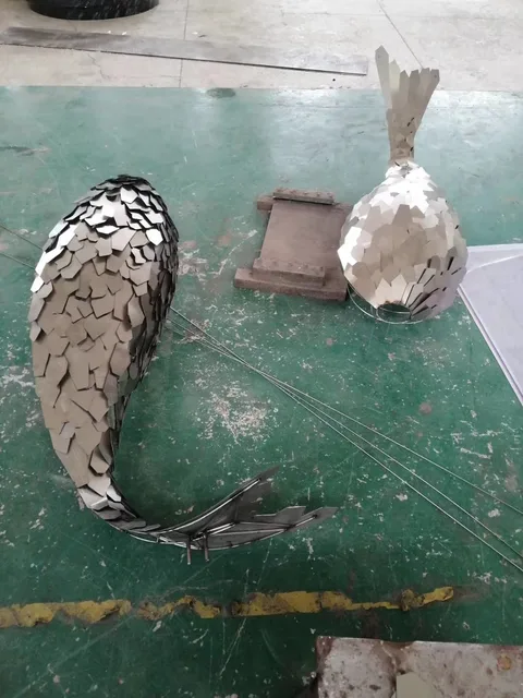 Large outdoor Luminous stainless steel fish sculpture shown in its setting