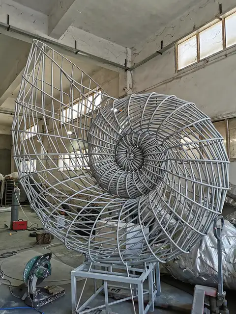 Large outdoor stainless steel conch sculpture seen from another angle