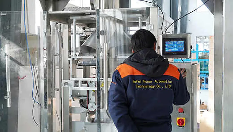 A Hefei Honor engineer setting packing parameters on the PLC touch screen during a run-off