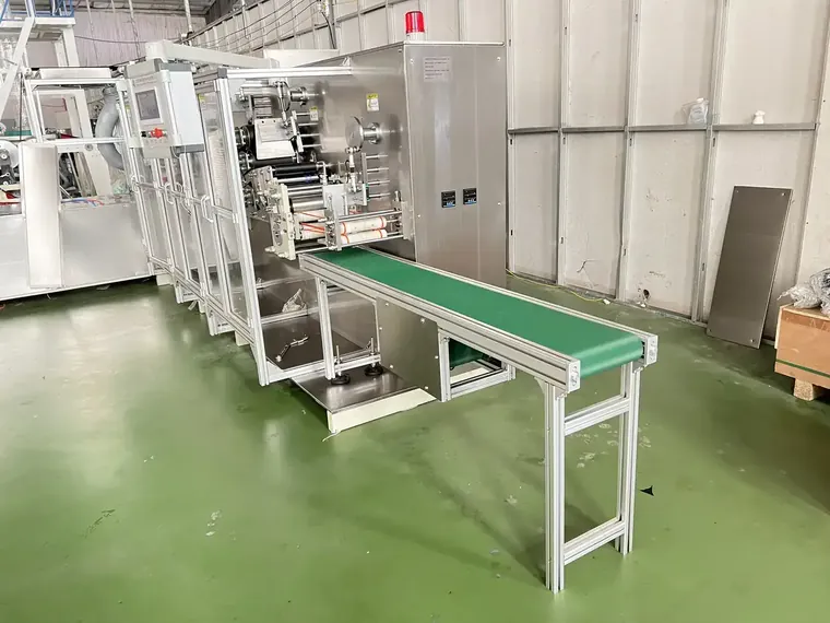 Apron machine under factory run-off, with the servo printing and folding sections set against a customer sample.