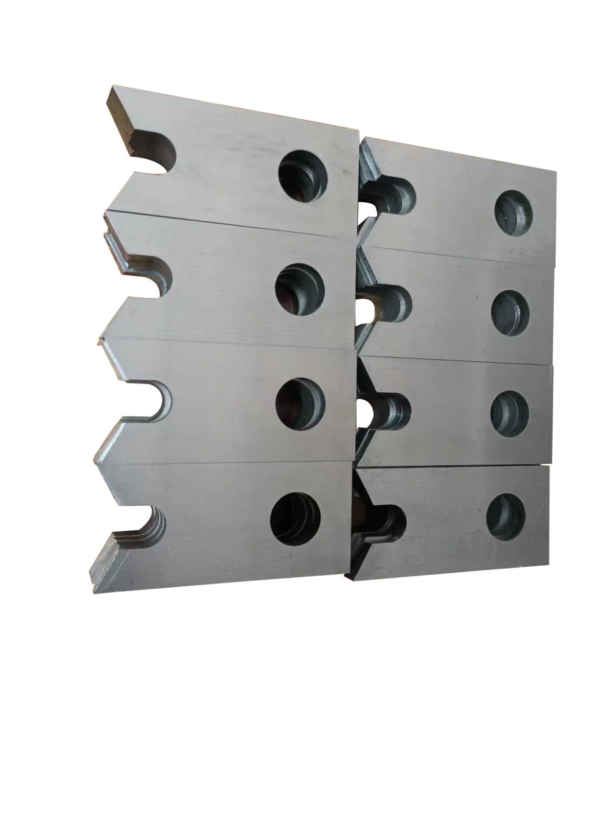Machined metal shear blades stacked against a black background
