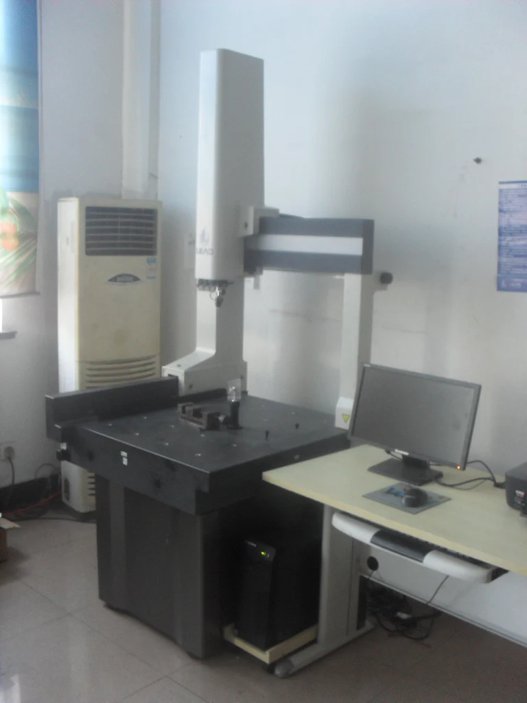 Coordinate measuring machine setup in an office or lab beside a computer desk