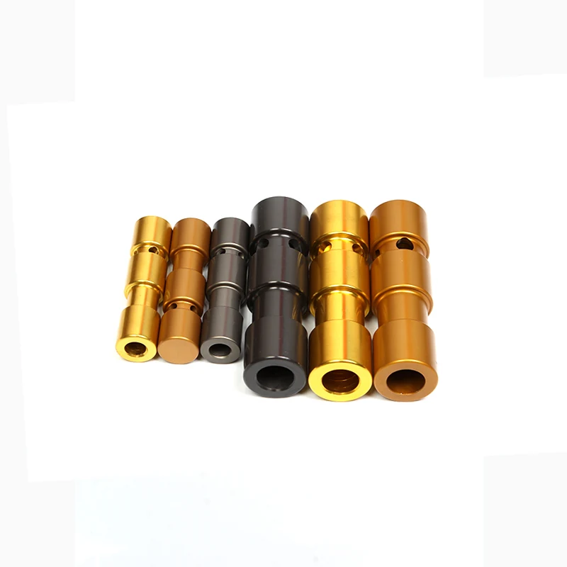 Assortment of gold, bronze, and black anodized aluminum cylindrical machined parts arranged on a white background.