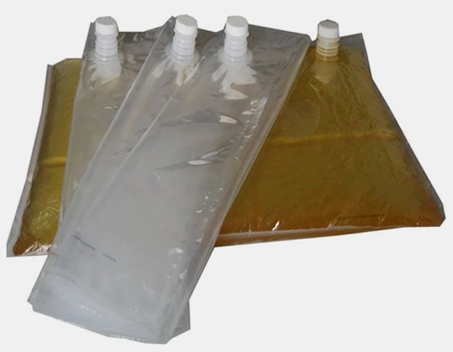 Four clear plastic spout pouches, two filled with amber liquid on white